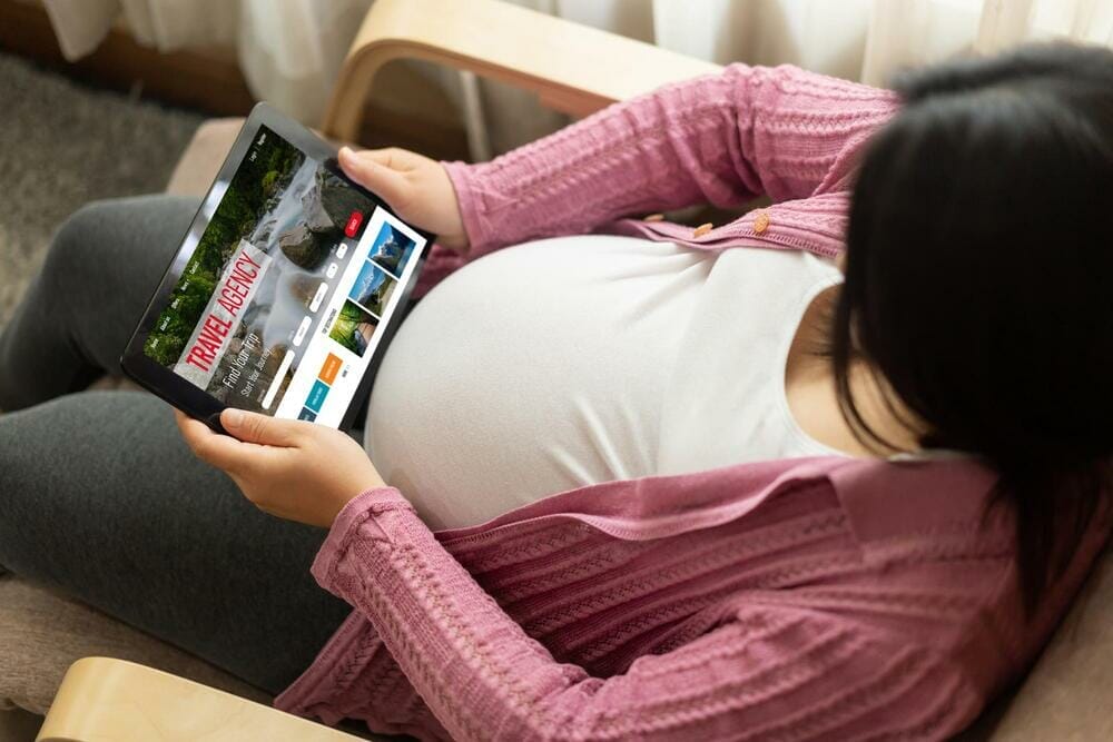 Pregnant woman searching online travel agency website